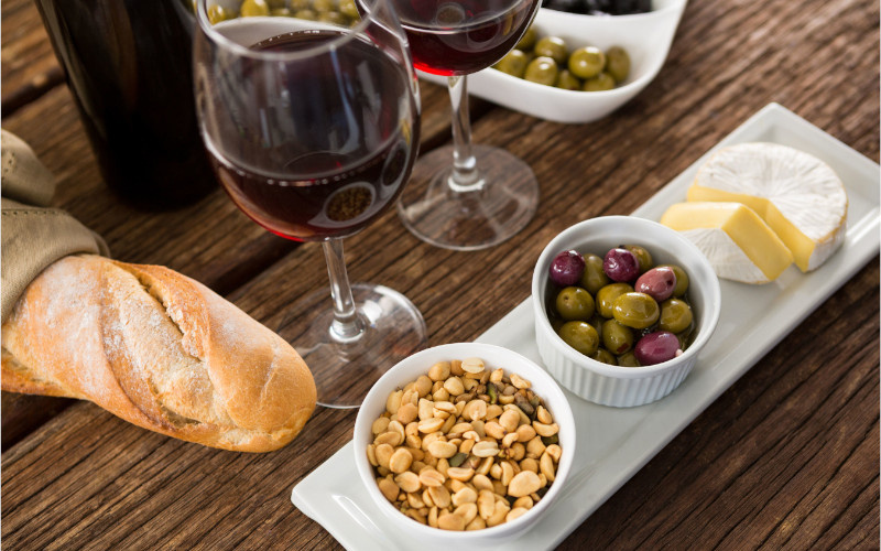 glass of wine bread olives peanuts cheese